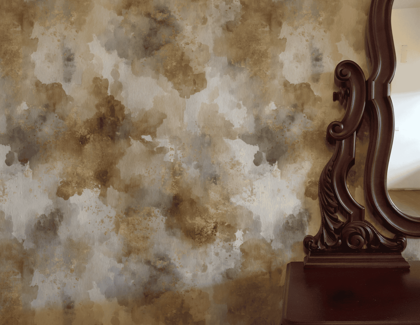 An ornate wooden mirror and dresser with golden accents stand beside a wall adorned in Sienna Drift Wallpaper, featuring abstract brown and gray tones that create an organic ambiance.