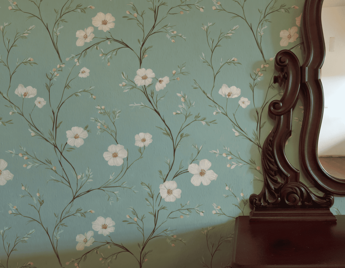 A close-up of Blossom Grace Wallpaper, featuring blue floral patterns and white blossoms beside an ornate dark wood mirror frame and dresser, creating a serene atmosphere.