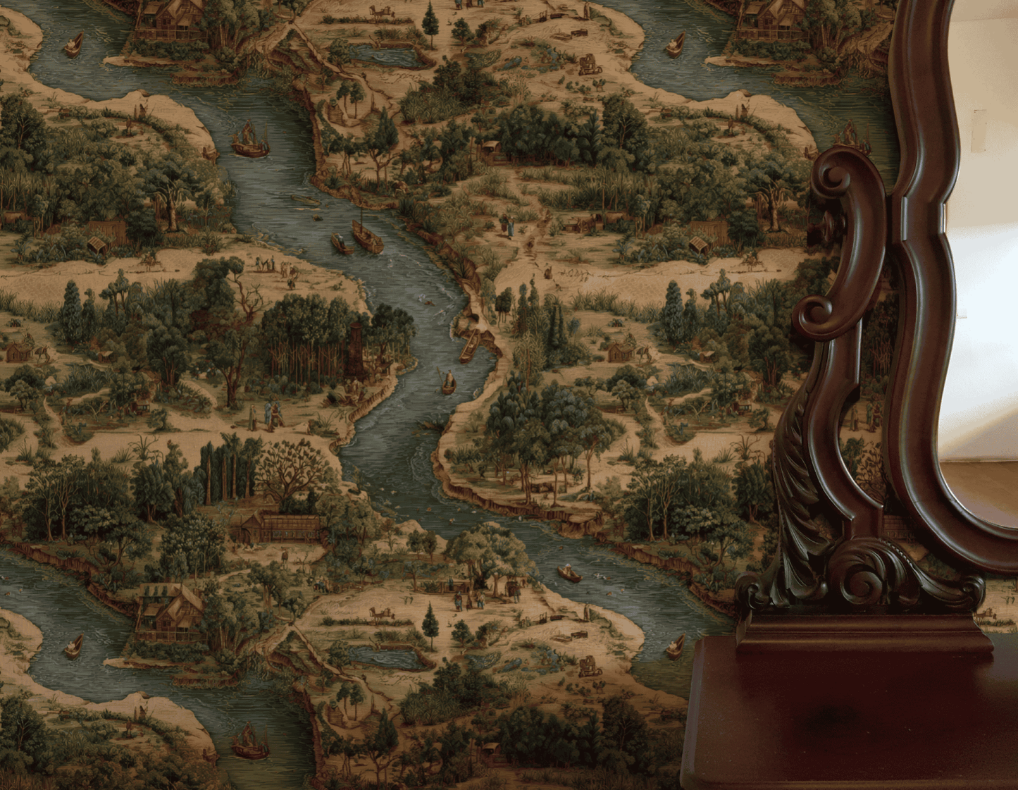 A vintage wooden mirror stands beside Riverside Tale Wallpaper, which features a whimsical landscape of flowing rivers, trees, boats, and small houses in muted colors.