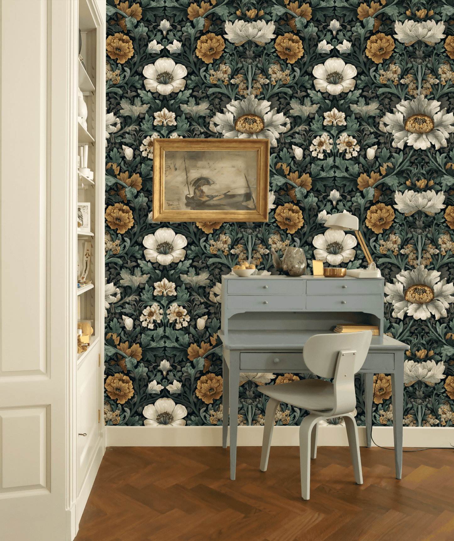 A small blue desk with a chair sits against Elysian Flora Wallpaper; a framed bird painting above the desk brings timeless elegance to the room’s wooden flooring.