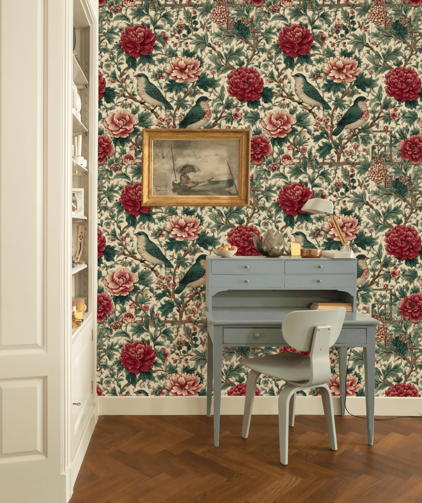 A small blue desk and chair sit against a wall adorned with Peony Birds Wallpaper, featuring elegant florals and birds; above the desk hangs a framed bird painting.