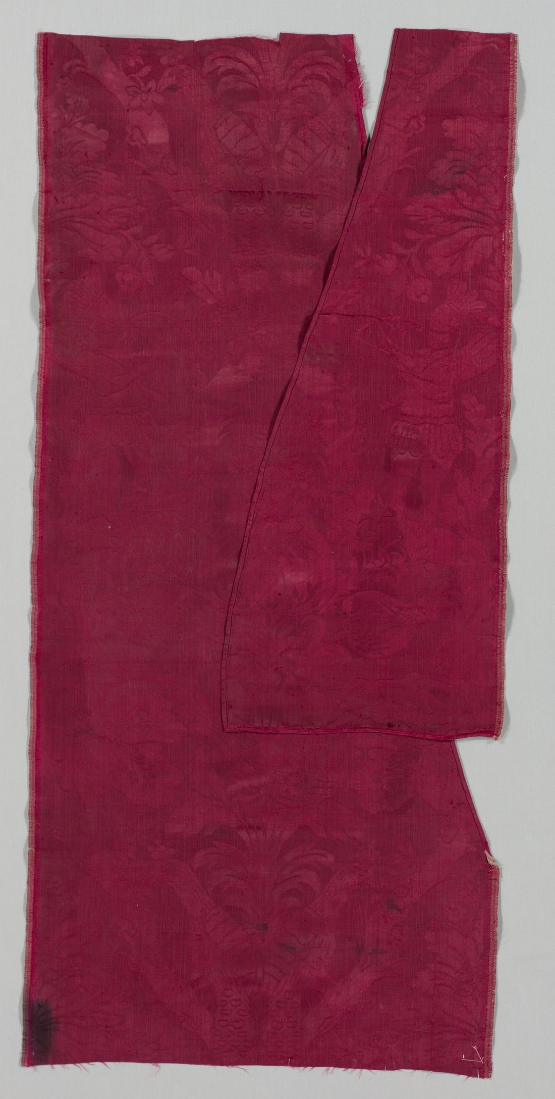 Tone-on-tone damask fabric showing a foliage scroll pattern woven in a single deep red color