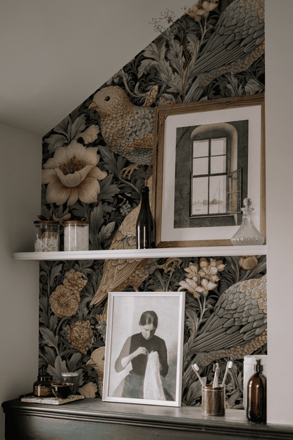 Shelf with glass jars, vases, and framed artworks stands before Garden Reverie Wallpaper, which features birds and blooms; a portrait and window art enhance the delicate charm of this elegant display.