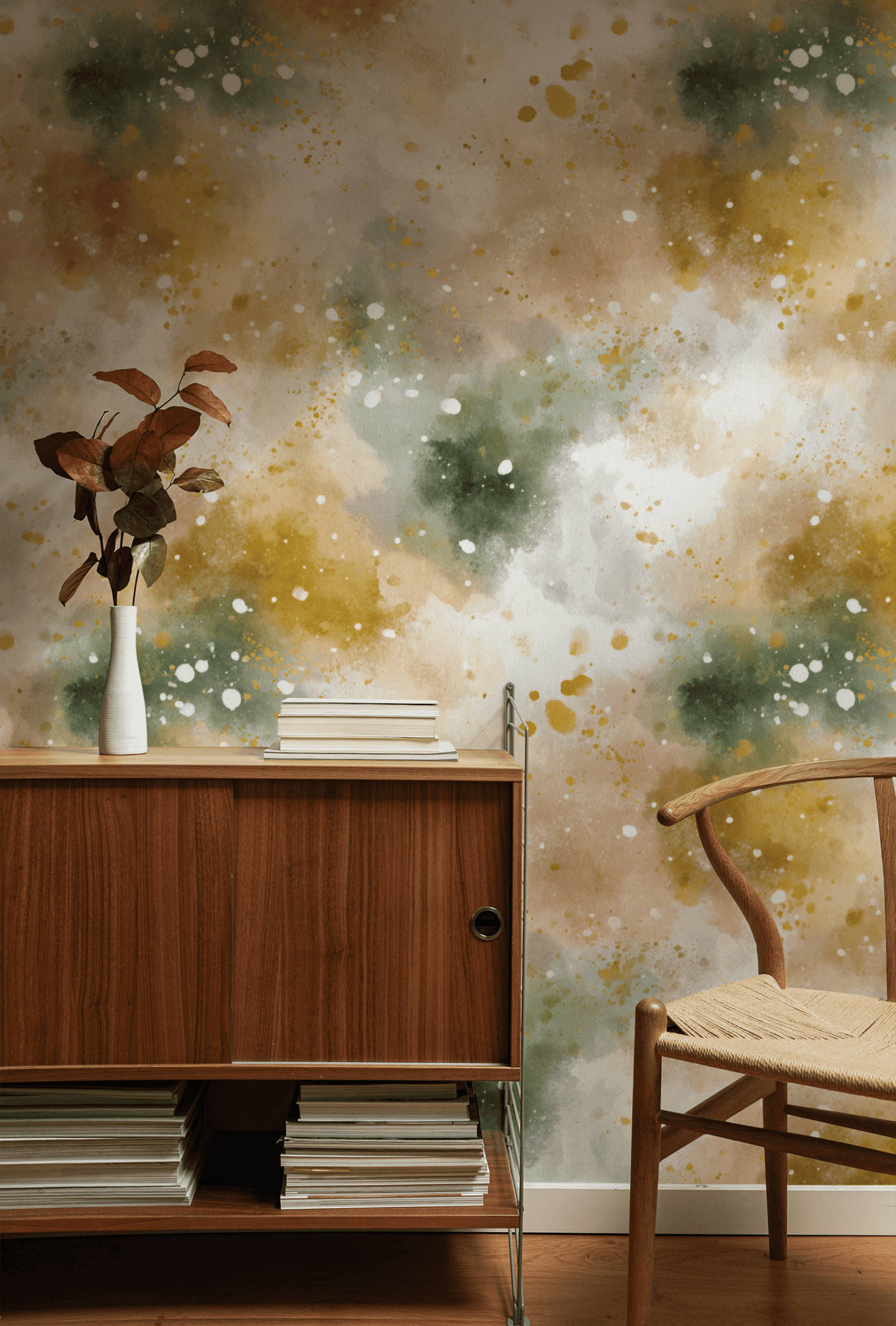 A wooden cabinet with books and a white vase of brown leaves stands against a wall decorated with Aurora Mist Wallpaper. Nearby, a wooden chair with a woven seat completes the serene setting.