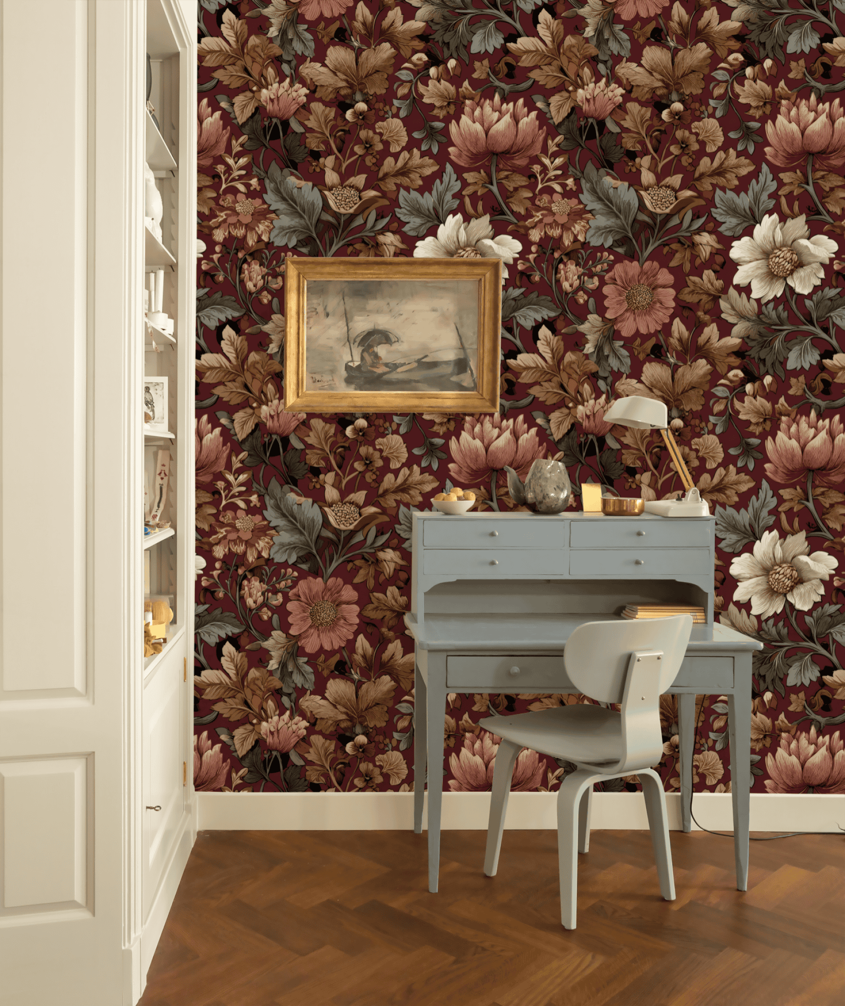 A small pale blue desk and chair set against a wall with Crimson Blossom Wallpaper, featuring a framed painting above the desk and built-in shelves on the left, creates a nook of timeless grace.
