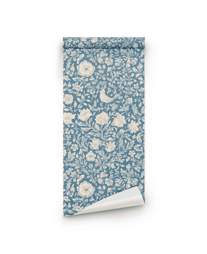 The Whimsical Meadow Wallpaper features a serene blue background with a cream floral and bird pattern, evoking whimsical tranquility as it lies partially unrolled on a white surface.