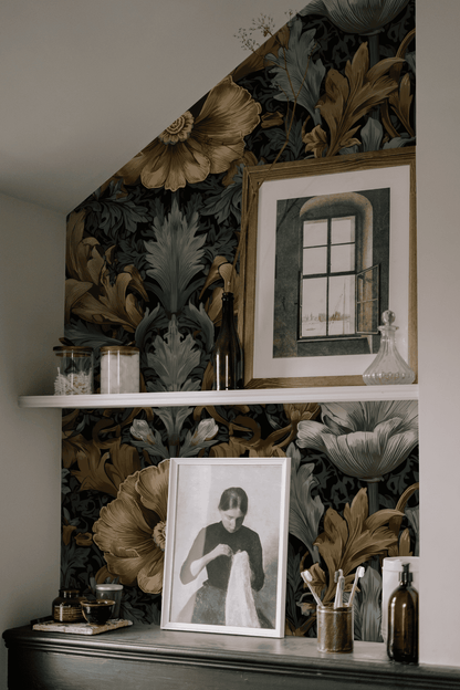 A wall adorned with Midnight Blooms Wallpaper exudes timeless elegance, featuring two framed pictures, glass jars, and decorative bottles arranged on a white shelf and a black surface below.