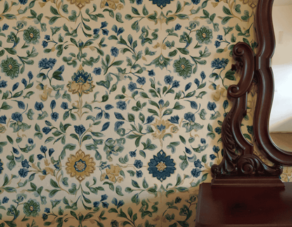 Bloom Haven Wallpaper in soft greens and blues creates a serene atmosphere, complemented by a dark wooden mirror and the edge of a wooden table on the right.