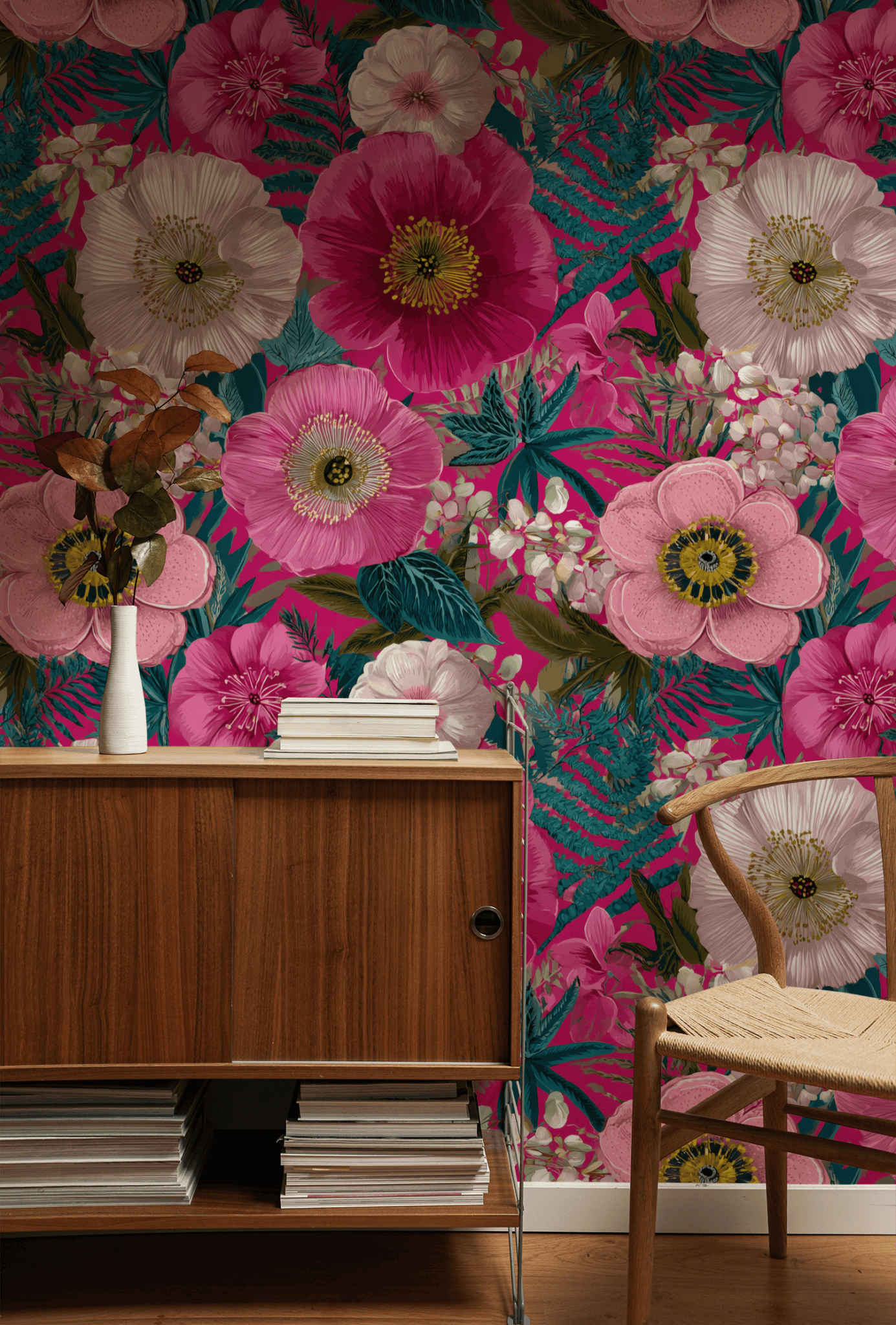 A wooden sideboard topped with a vase of dried flowers sits before Blossom Fantasy Wallpaper in pink, white, and green—a true floral celebration—beside a woven seat chair.