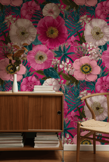 A wooden sideboard topped with a vase of dried flowers sits before Blossom Fantasy Wallpaper in pink, white, and green—a true floral celebration—beside a woven seat chair.