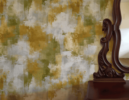 A decorative wooden mirror stands beside a wall adorned with Golden Essence Wallpaper, infusing the space with golden hues and an abstract aesthetic.