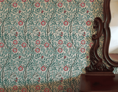 Red Floral Wallpaper installed on a room wall with the Morris sweet briar rose design in warm light Victorian palette