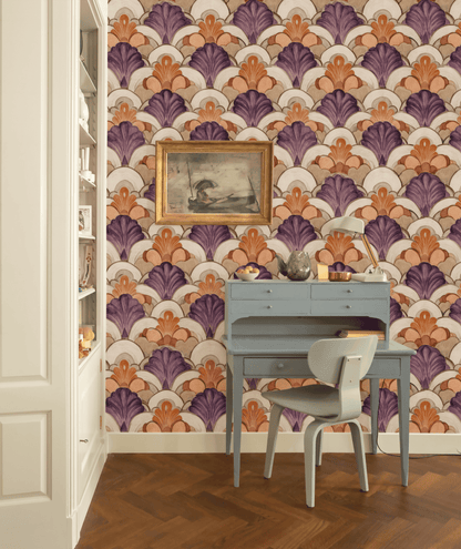 A small blue desk and chair sit in front of Deco Bloom Wallpaper, featuring colorful Art Deco fan patterns in purple and orange with floral accents; a framed painting hangs above the desk.