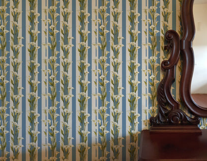 White calla lilies climbing a blue-and-white vertical cabana stripe in a fresh classic wallpaper. - room view