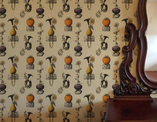 Surreal still-life wallpaper of pears and tomatoes on cinderblocks with chains, a hand and calla lilies on cream.