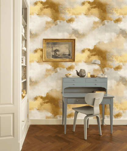 A small blue writing desk with a chair is set against Golden Haze Wallpaper. A painting, lamp, and decorative items rest on the desk, while bookshelves are visible to the left.
