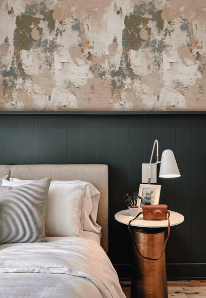 A modern bedroom with a beige upholstered bed and striped pillow exudes elegance, featuring a round side table with decor, set against a dark green paneled wall and Rustic Plaster textured abstract wallpaper.