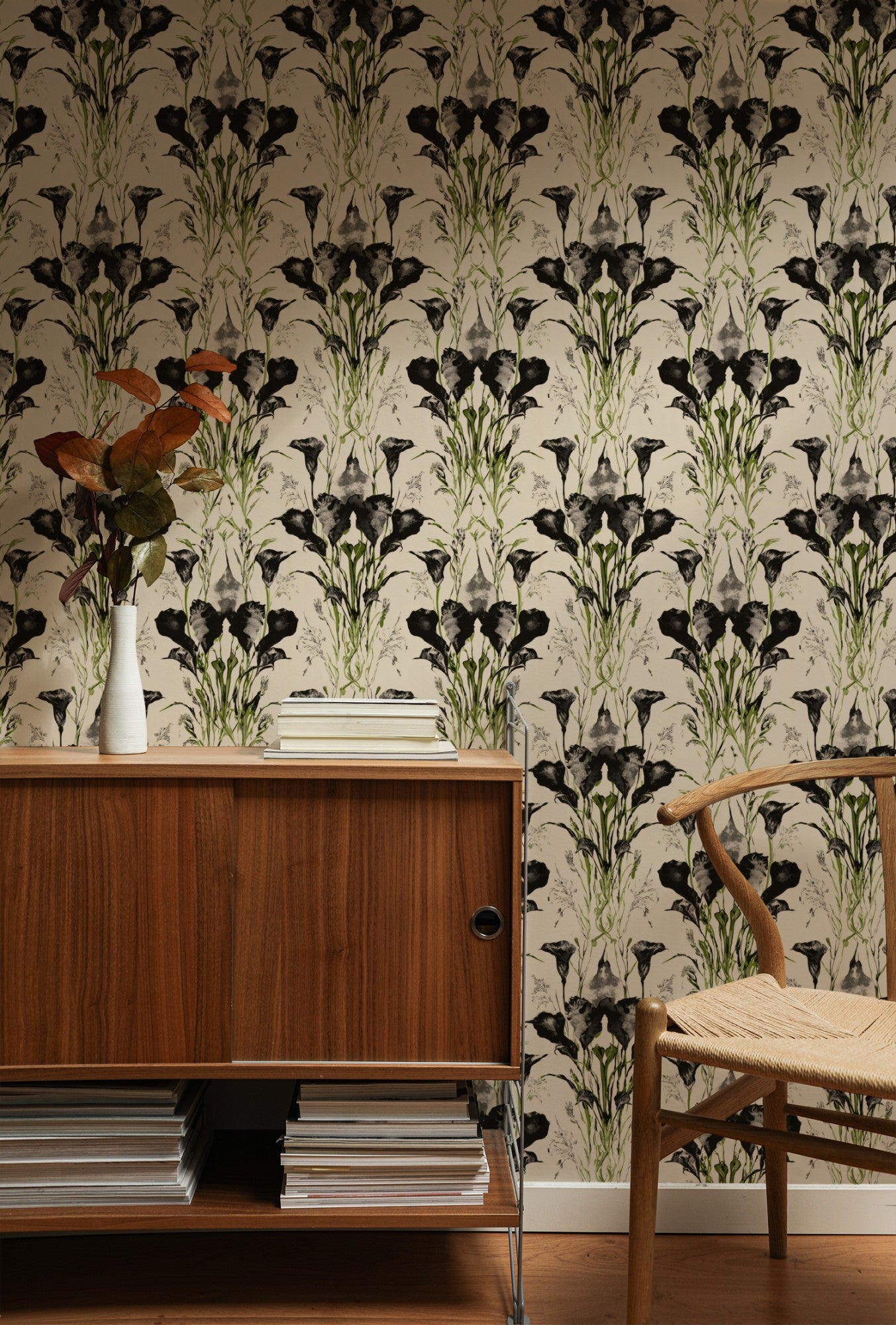 Symmetrical black-ink calla lilies and grasses with green accents on a cream ground in a dramatic wallpaper. - room view
