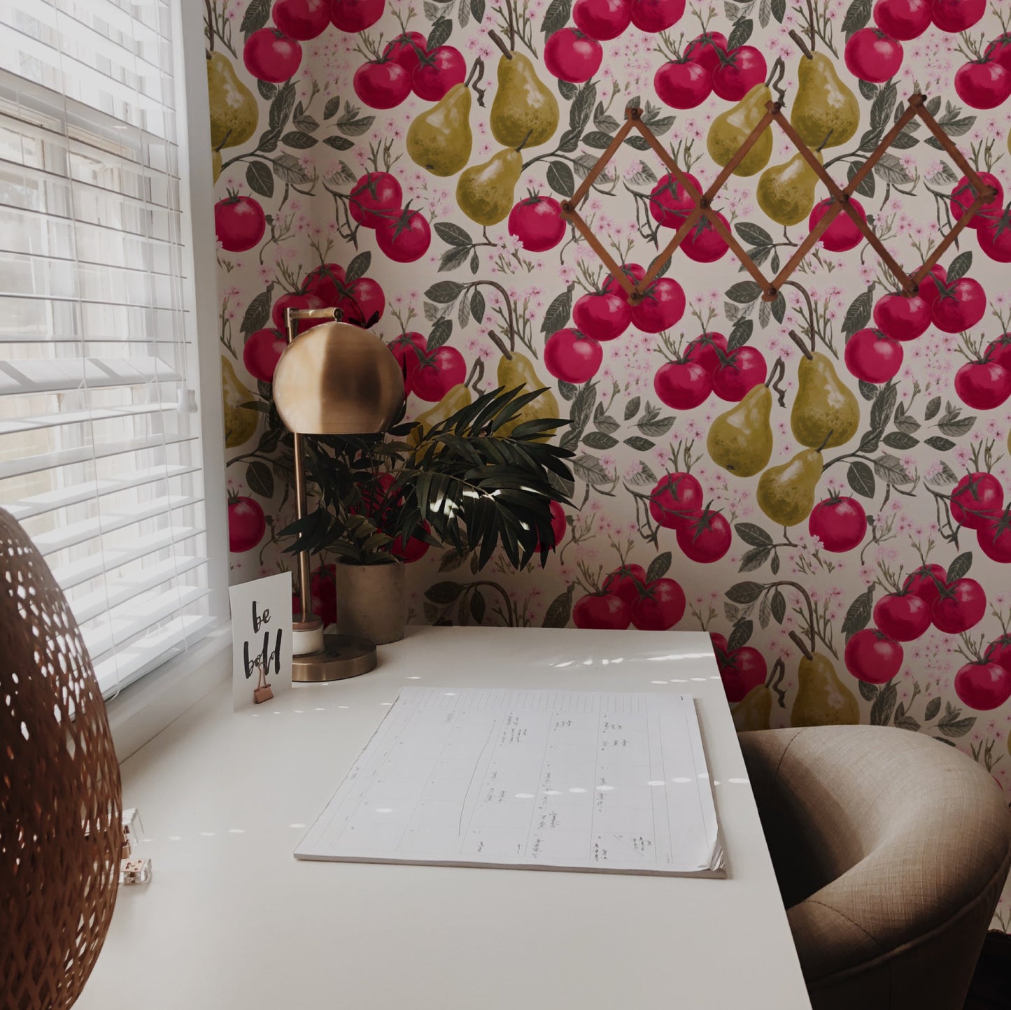 Crimson tomatoes and golden pears with pink cherry blossom on a warm cream ground in a lush fruit wallpaper.