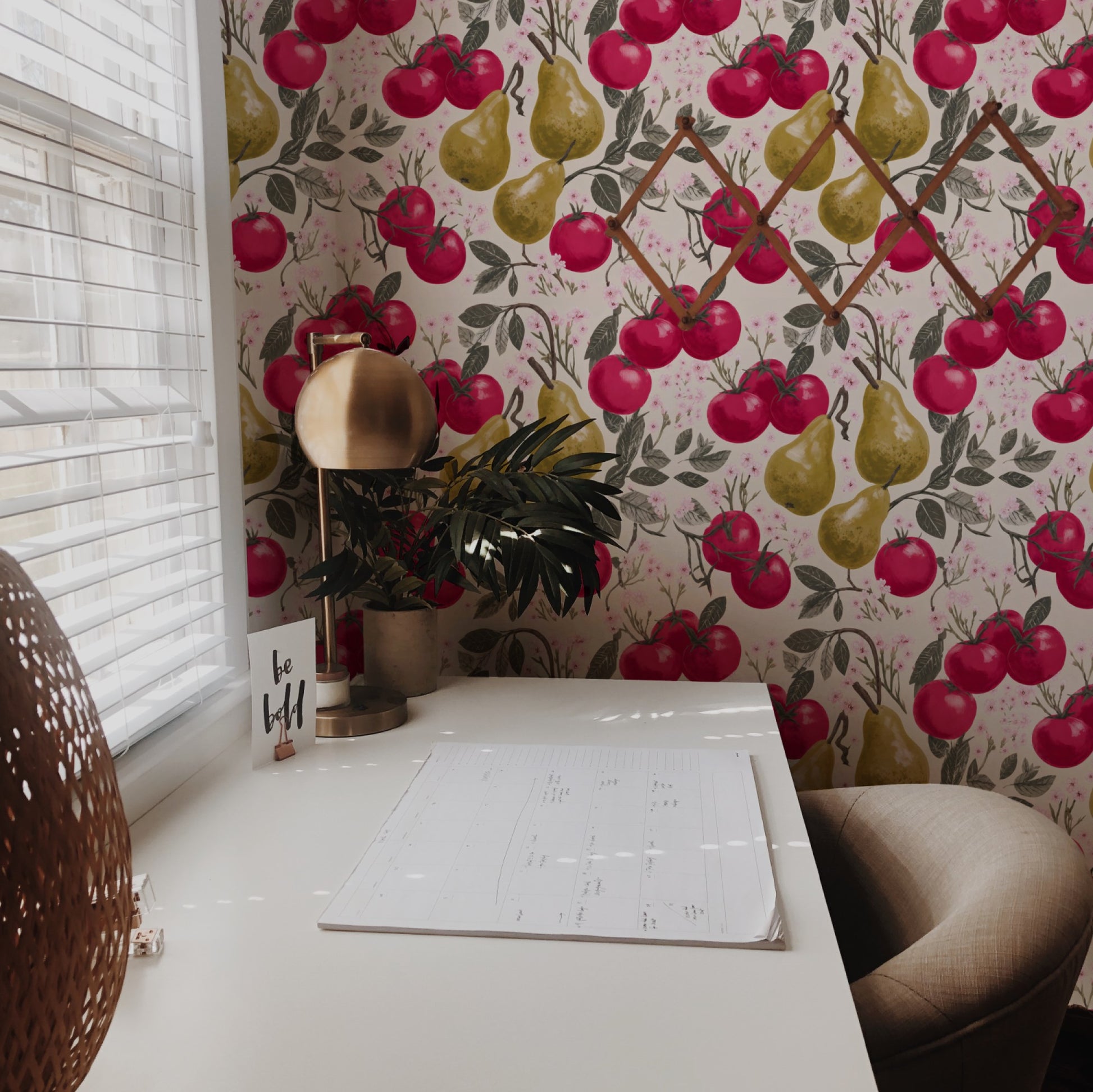 Crimson tomatoes and golden pears with pink cherry blossom on a warm cream ground in a lush fruit wallpaper.