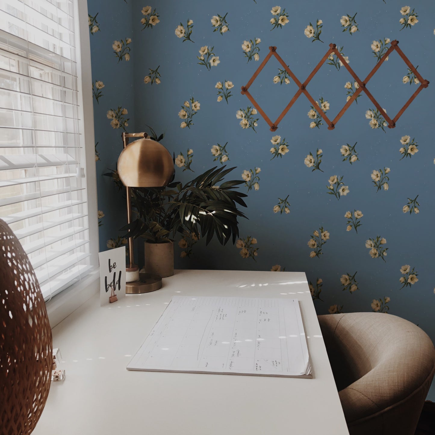 Cream wildflower sprigs scattered across a soft dusty-blue ground in a delicate painterly ditsy wallpaper. - room view