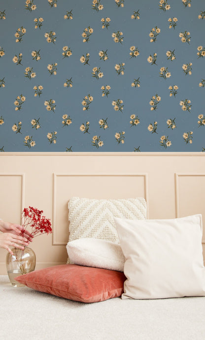 Cream wildflower sprigs scattered across a soft dusty-blue ground in a delicate painterly ditsy wallpaper. - room view