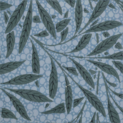 Dark slate willow leaves on curving stems over a dusty-blue ringed ground, a William Morris design.